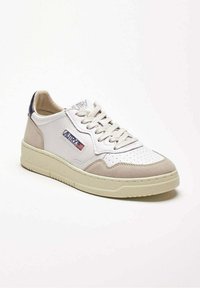 Sneaker bianca a taglio basso con dettagli in suede beige, lacci, punta traforata e una toppa con il logo della bandiera americana sul lato.