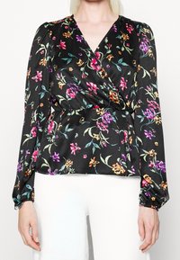 Svart blommig omslagsblus med färgglada blommor, långa puffärmar, en smockad midja och mjuk satintextur.