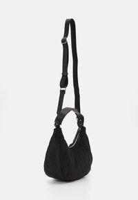 Sac à épaule en nylon noir avec une forme incurvée, des accents en cuir et une fermeture éclair. Il dispose d'une sangle réglable et d'une texture lisse.