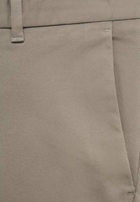 Bežová látka na kalhoty s jemnou žebrovanou strukturou a boční kapsou, vybavená hladkým pasem a minimálními detaily švů.