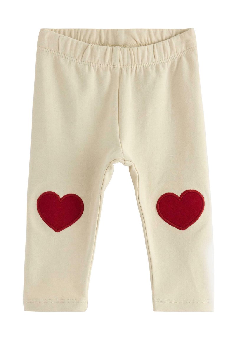 Beige leggings med en strækbar talje, der har to røde hjerteapplikationer på knæene. Blødt bomuldsstof.
