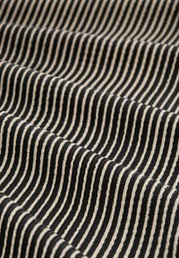 Tessuto con strisce orizzontali alternate nere e avorio, caratterizzato da una superficie texturizzata che crea un effetto ondulato distintivo.