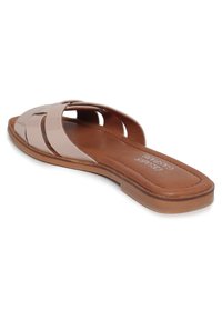 Platte schuif sandaal met een glanzende nude lak buitenkant, crisscross bandontwerp en een tan gevoerde binnenzool. Geen hak, minimalistische silhouet.