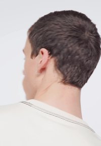 Camicia crema a maniche corte con dettagli di cuciture nere al colletto, vista da dietro, che mette in mostra un tessuto testurizzato e un design slim fit.