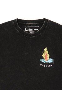 Sort løst fit T-shirt med rund halsudskæring. Den har et farverigt grafik af en hånd med en flamme og ordet "VOLCOM" nedenunder.