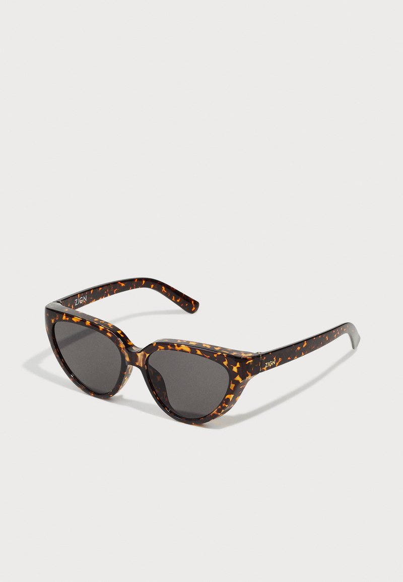 Tortoiseshell cat-eye sunglasses with dark lenses, featuring a glossy finish and angular shape, highlighted by orange speckles in the frame.