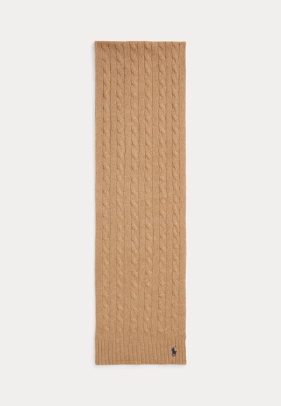 Kamel-farget kabelstrikket ullsjal med ribbestrikkede ender og liten marineblå brodert logo nær kanten på hvit bakgrunn.