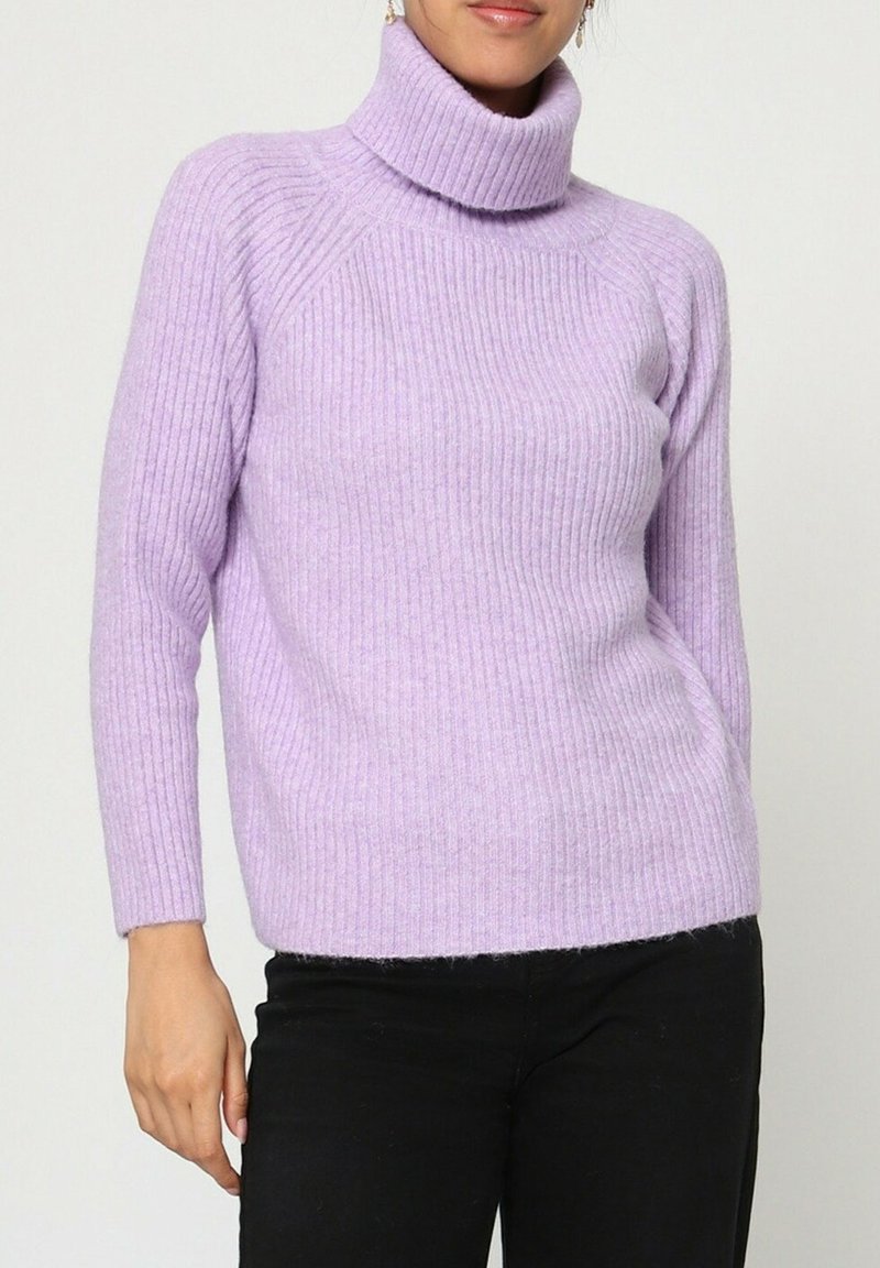 Pull en tricot côtelé violet avec un col haut et des manches longues, doté d'une coupe décontractée et d'une texture douce. Porté avec un pantalon sombre.