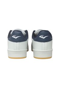Sneaker bianchi e blu navy con una finitura in pelle liscia, tacco arrotondato e suola in gomma. Logo bianco notevole sul tallone.