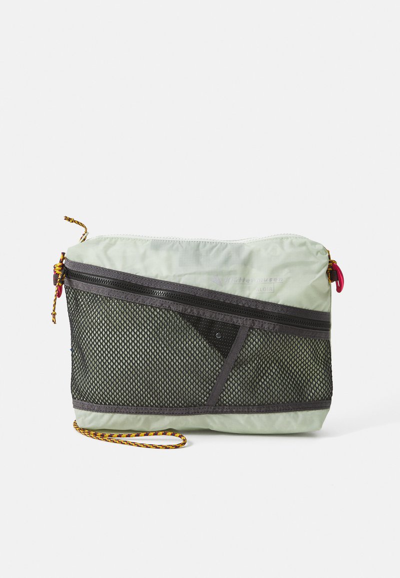 Light green nylon bag with a black mesh front, top zipper closure, and a patterned strap. Features a triangle design and colored zipper pull.