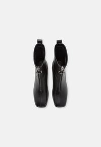 Bottines en cuir noir avec un bout carré, dotées d'une fermeture éclair centrale et d'une languette, texture lisse et design épuré.