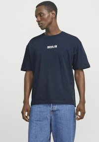 Marineblå bomulds T-shirt med korte ærmer og rund hals, med hvid "SEOUL" tekst trykt på brystet. Klassisk afslappet pasform.
