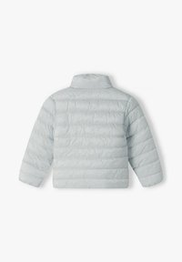 Ljust grått pufferjacka med hög krage, med horisontella kviltade mönster och långa ärmar. Slät, lätt material.