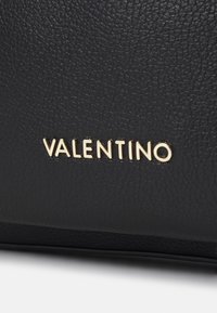 Svart läderväska med en texturerad yta och en guld "Valentino"-logotyp som är tydligt framhävd. Enkel, elegant design med minimala accenter.