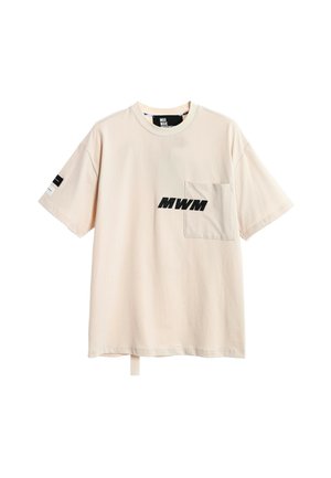 Camiseta beige de manga corta con bolsillo delantero en el pecho izquierdo, texto negro "MWM" en el bolsillo y pequeño diseño en blanco y negro en la manga derecha.