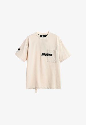 Camiseta beige de manga corta con bolsillo delantero en el pecho izquierdo, texto negro "MWM" en el bolsillo y pequeño diseño en blanco y negro en la manga derecha.
