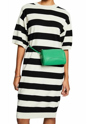 Personne portant une robe rayée horizontale noire et blanche avec une petite sacoche en cuir verte attachée autour de la taille.