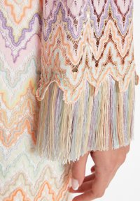 Robe au crochet multicolore avec un motif en zigzag, accentuée de nuances pastel d'orange, de violet et de menthe, ornée de longues franges brillantes.