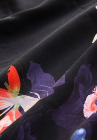 Tessuto a motivo floreale con vivaci fiori rossi, viola e blu su uno sfondo nero, realizzato in materiale liscio e leggero.