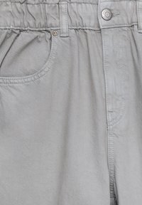 Pantalon gris clair avec une taille élastique, une poche avant, une boucle pour ceinture et une fermeture à bouton sur le côté droit.