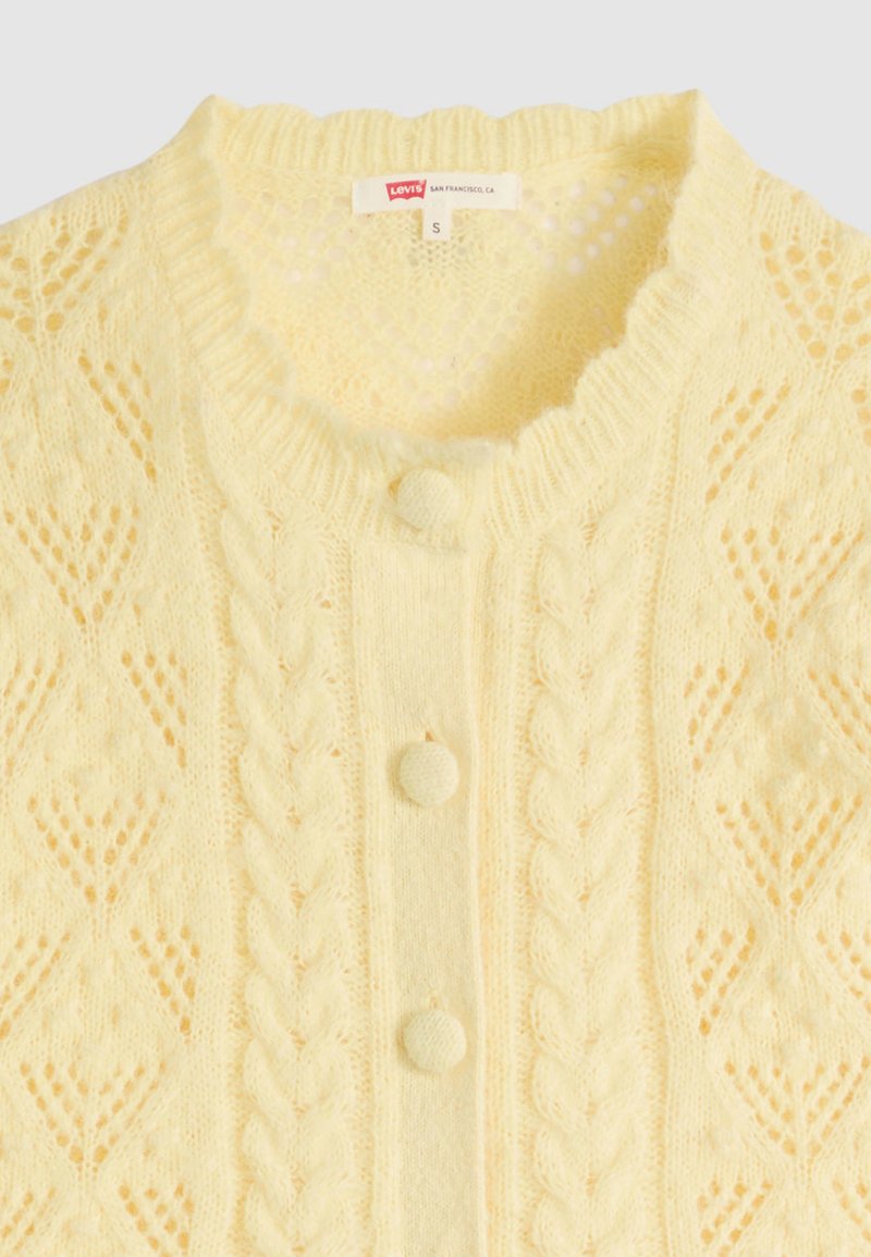 Soft yellow knitted cardigan with cable patterns, three fabric-covered buttons, and a small Levi's brand label at the neckline.