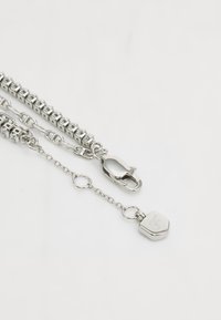 Collana in argento con maglie quadrate intrecciate, chiusura a gancio e un piccolo pendente esagonale con un design inciso.