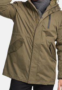 Olivgrüne isolierte Jacke mit Kapuze, großen seitlichen Taschen, einem Reißverschluss vorne und strukturiertem Stoff.