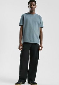 Lichtblauwe katoenen t-shirt met een ronde hals, gecombineerd met zwarte cargobroeken met zijzakken en een losse fit.