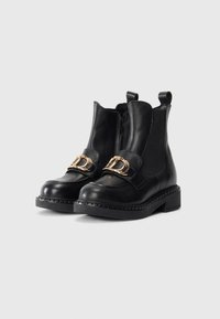 Bottines à talon chunky en cuir noir avec un bout arrondi, fermeture éclair, matériel décoratif en finition dorée et une texture détaillée avec des coutures.