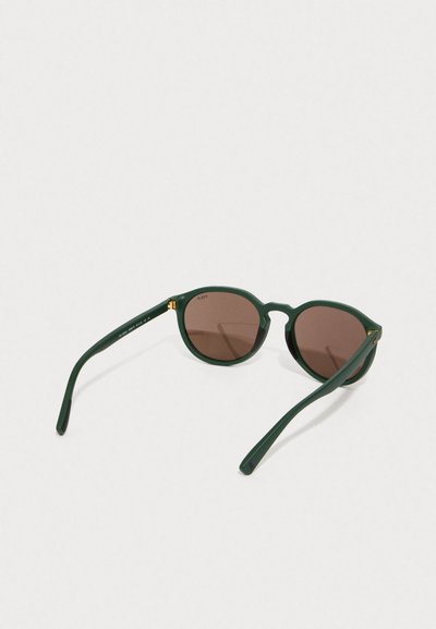 Óculos de sol verdes em formato redondo com lentes castanhas. Acabamento mate, hastes finas com detalhes em dourado. Possui uma armação de plástico leve.
