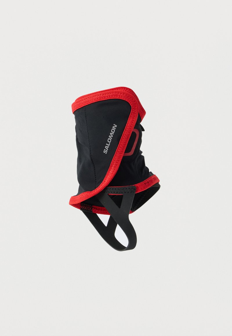 Μαύρο και κόκκινο καλύμμα αστραγάλου Salomon με ελαστικό ιμάντα ποδιού, σχεδιασμένο για προστασία των αστραγάλων σε εξωτερικούς χώρους και πρόληψη εισόδου σκουπιδιών.