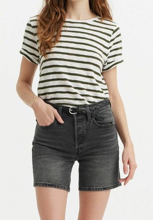 Stribet t-shirt i grøn og hvid, korte ærmer, parret med højtaljede sorte denimshorts, som har et flettet sort bælte.