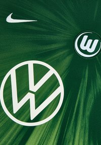 Maglietta verde con logo Nike bianco ed emblema Volkswagen. Il tessuto ha una texture morbida con motivi radiali dinamici.