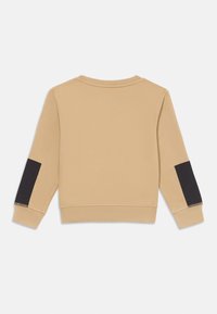 Sudadera beige de manga larga con parches negros en los codos, cuello redondo y puños y dobladillo de canalé, mostrada desde la parte trasera sobre un fondo blanco.