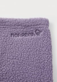 Violetinė flokšinė medžiaga su minkštu, tekstūruotu paviršiumi; puikuojasi išsiuvinėtu "NORRØNA" logotipu. Dizainas yra paprastas ir funkcionalus.