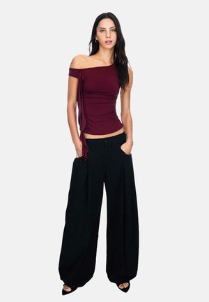 Burgundy off-shoulder top with ruched side detail, paired with loose black wide-leg pants. Smooth fabric, relaxed fit, minimal accents.