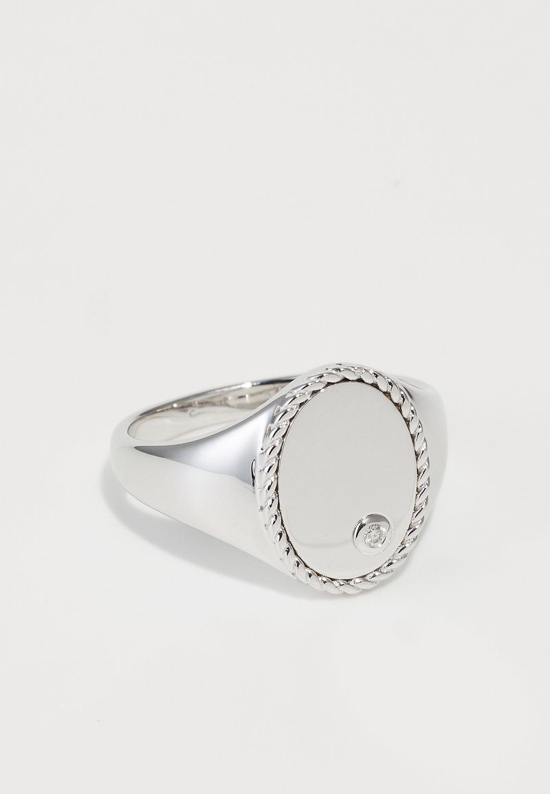 Anello d'argento con una parte superiore piatta, tonda e liscia, caratterizzato da un piccolo accento di diamante e dettagli in corda attorcigliata lungo il bordo.