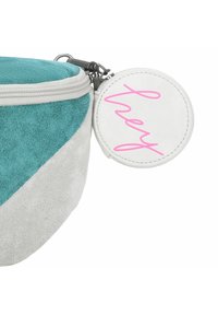 Ronde tas in teal en grijs suede, met een rits en een ronde witte tag met roze script tekst die "hey" zegt.