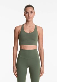 Olivno zelena športna modrca z debelimi naramnicami, okroglo izrezom in ujemajočimi se hlačami z visokim pasom. Gladek, raztegljiv material brez vidnih vzorcev.