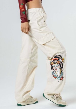 Cargo pants in cream, made from cotton, feature an embroidered geisha design on the left leg. Includes side pockets and an elastic waistband.