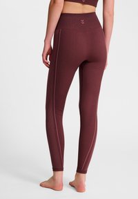 Bordowe legginsy z wysokim stanem, z pionowym fakturowaniem i różowymi paskami akcentującymi po bokach. Miękki, elastyczny materiał.