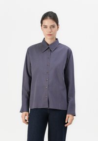 Chemise à manches longues avec boutons, fabriquée dans un tissu bleu lisse avec de fines rayures verticales en bleu foncé et bordeaux. Elle possède un col classique.