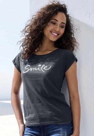Dark gray short-sleeve T-shirt featuring white script "Smile" design. Soft fabric with a relaxed fit, paired with denim shorts.