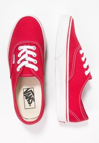 Rote Canvas-Sneaker mit weißen Schnürsenkeln, Gummisohlen und einem weißen Streifen. Enthält das Vans-Logo auf der Innensohle und hat eine glatte Textur.