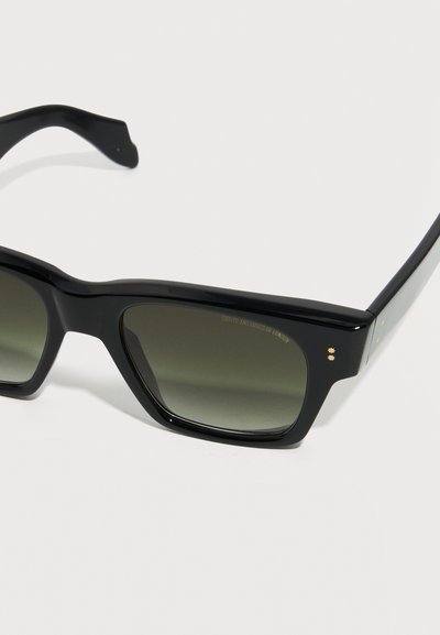 Sorte rektangulære solbriller med mørke gradientlinser på hvid baggrund, der viser delvis stel og stænger.