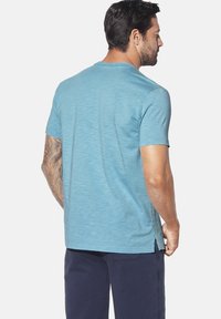 Blue short-sleeve t-shirt, soft texture, crew neckline, relaxed fit, with side slits and stitched accents along the seams.