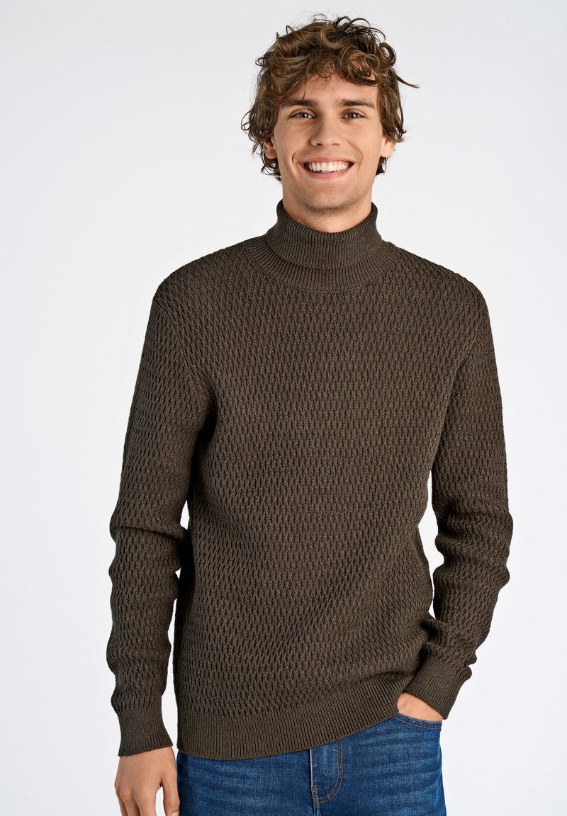 Brauner gestrickter Rollkragenpullover mit einem strukturierten Rautenmuster, gerippten Bündchen und Saum, kombiniert mit blauen Jeans. Lässiger, figurnaher Stil.