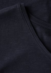 Tmavě navy látka s hladkým povrchem, s výstřihem do V a jemnými horizontálními vzory. Okraje mají plochý steh.