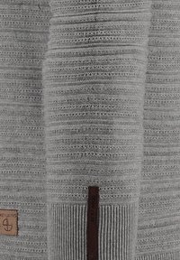 Szary sweter dziany z prążkowanymi mankietami i teksturowanymi wzorami. Posiada skórzaną metkę marki z napisem „KEY LARGO”.