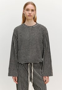 Gestreepte zwart-witte oversized sweatshirt met lange mouwen, ronde hals, ribgebreide manchetten en een ontspannen pasvorm. De stof heeft een zachte textuur.